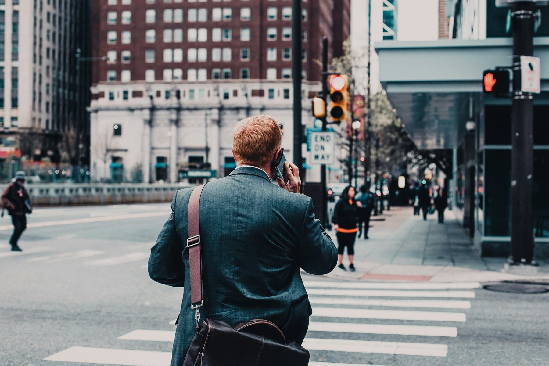 A professional crossing a downtown street at dusk